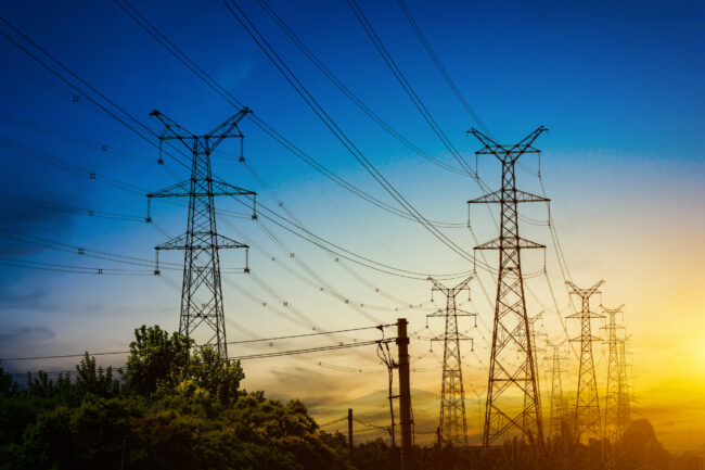 Sun setting behind the silhouette of electricity pylons tributo-na-veia-3